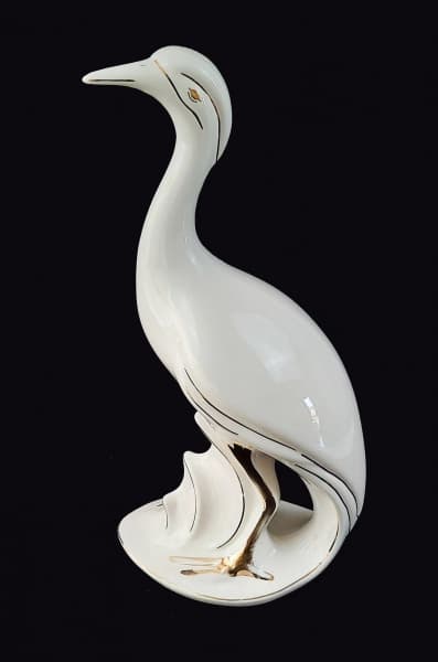 DELLA ROBBIA - Escultura de garça em cerâmica nas tonalidades branco e dourado (Apresenta desgastes na pintura dourada). Altura 47cm e largura 17cm. — DELLA ROBBIA