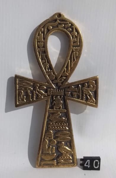 DIVERSOS, uma (1) cruz de ANSATA ou ANKN (cruz egípcia que simboliza o homem e a mulher em perfeita união), ornada com diversos hieroglifos, confeccionada em bronze, medindo 11,5 x 6 cm. — DIVERSOS