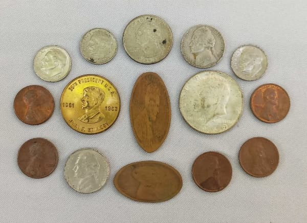 NUMISMÁTICA, USA, quinze (15) moedas diversas e afins: 1 de half dólar de PRATA 1969 D (cunhada em Denver); 1 de quarter dólar 1995; 3 de one dime 1965, 1978 e 1980; 2 de five cents 1970 S e 1985 P; 1 medalha alusiva ao Kennedy, confeccionada em bronze dourado, vide fotos, medindo 29 mm diâmetro, excelente estado de conservação; 5 de 1 cent 1974, 1975, 1977, 1980 D e 1980 (2); 2 placas souvenir de New York, ambas confeccionadas com moedas de 1 cent. — NUMISMÁTICA