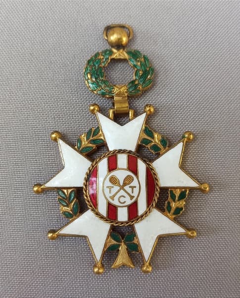 NUMISMÁTICA, uma (1) antiga medalha do TIJUCA TÊNIS CLUBE, confeccionada em bronze esmaltado, inspirada nas comendas francesas, falta o disco da parte traseira, impossibilitando a identificação do agraciado, medindo 70 x 50 mm. — NUMISMÁTICA