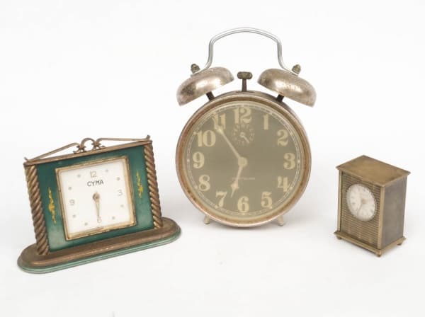 COLECIONISMO- TRIO DE RELÓGIO DE MESA, SENDO UM EM BRONZE DA MARCA MONDAIME MOSQUITO, SEM A TAMPA TRASEIRA, OUTRO RELÓGIO DESPERTADOR DA MARCA CYMA E OUTRO RELÓGIO DESPERTADOR WESTCLOX, AMBOS FUNCIONANDO, MAS SEM GARANTIAS DE FUNCIONAMENTO E APRESENTAM MARCAS E OXIDAÇÕES DO TEMPO. MEDIDA: 15 X 11 CM/ 8 X 13 CM/ 6 X 5 X 3,5 CM. — COLECIONISMO