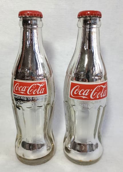 COLECIONISMO - Par de garrafas COCA-COLA com pintura metalizada, decorativas, em vidro, lacradas com tampa em metal. 20 cm, cada uma. — COLECIONISMO