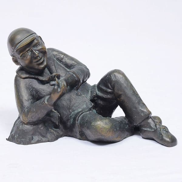 Cholby. Escultura de bronze representando figura de jovem com baralho nas mãos. Assinado. Alt. 20 e comp. 30 cm. — Cholby