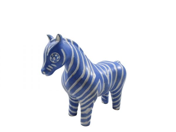 PABLO ZABAL (Chile), Escultura confeccionada em porcelana esmaltada na tonalidade branca representando zebra na tonalidade azul, apresenta colado no rabo, assinado no verso, medindo 16x21cm. — PABLO ZABAL