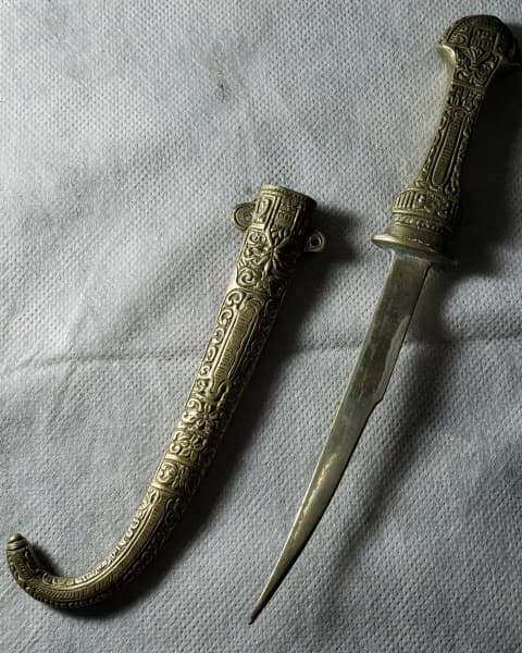 COLECIONISMO - ADAGA TURCA em bronze, ricamente cinzelada na empunhadura e em toda bainha, ponta fina com leve torção, medindo o conjunto 23 cm X 5 cm na maior largura e pesando 200 gramas. — COLECIONISMO