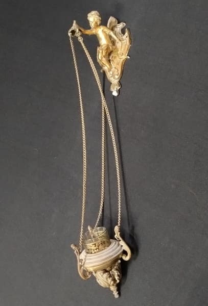 COLECIONISMO---ANTIGO,ELEGANTE,COMPRIDO E DECORATIVO CASTIÇAL DE PAREDE--DELICADA PEÇA ENCIMADA POR FIGURA DETALHADA DE "PUTTO",EM BRONZE DOURADO-- CORRENTE EM PEQUENOS ELOS E COPO PARA VELA EM VIDRO TRANSPARENTE --- Med:60cm comp. — COLECIONISMO