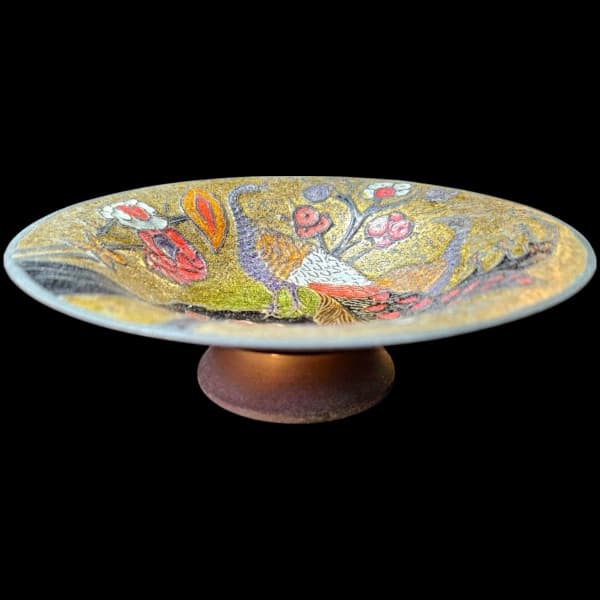 ENCANTADORA FRUTEIRA EXECUTADA EM METAL, AO GOSTO DITO CLOISONEÉ, ORNADA EM MOTIVOS FLORAIS, VEGETALISTAS E PAVÃO RICAMENTE POLICROMADA SOB HASTE CIRCULAR, MEDINDO 4 X 15 CM. APRESENTA MARCAS DO TEMPO E/OU USO. BREVE BIOGRAFIA: ORIGEM BIZANTINA E FOI INTRODUZIDA NA CHINA NO SÉCULO XIV, TÉCNICA DE TRABALHO EM ESMALTE NA QUAL TIRAS FINAS DE METAL SÃO COLADAS SOBRE UMA SUPERFÍCIE, FORMANDO UM DESENHO COMPOSTO POR VÁRIOS PEQUENOS COMPARTIMENTOS PREENCHIDOS COM PASTA DE ESMALTE VITRIFICADO. ESTE LOTE — ENCANTADORA FRUTEIRA EXECUTADA EM METAL